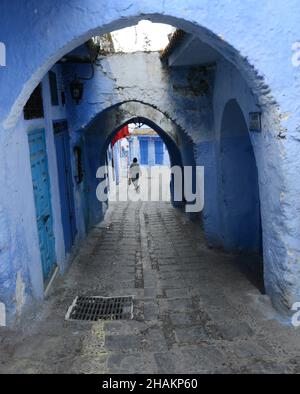 Un uomo locale che cammina per le strette strade della medina di Chefchaouen, Marocco. Foto Stock