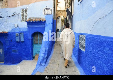 Un uomo locale che cammina per le strette strade della medina di Chefchaouen, Marocco. Foto Stock
