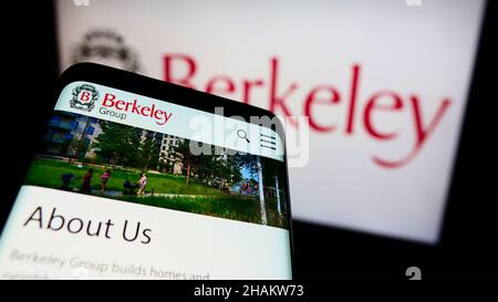 Telefono cellulare con pagina web della società britannica The Berkeley Group Holdings plc sullo schermo di fronte al logo. Mettere a fuoco sulla parte superiore sinistra del display del telefono. Foto Stock