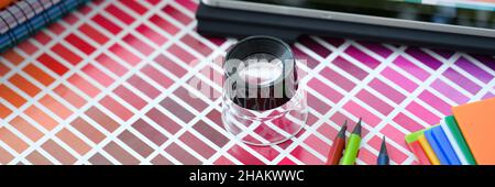 Piccola lente di ingrandimento sulla parte superiore della tavolozza dei colori e campioni con diverse tonalità di colore primo piano Foto Stock