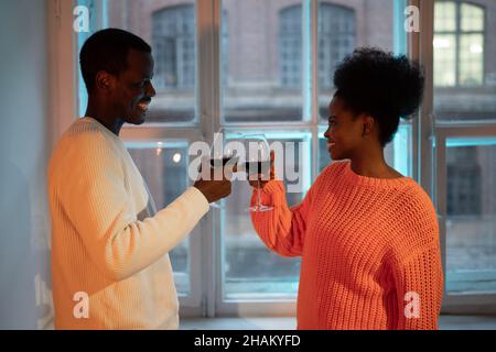 Felice coppia africana godere romantica data a casa, famiglia biraciale moglie e marito bere vino rosso Foto Stock
