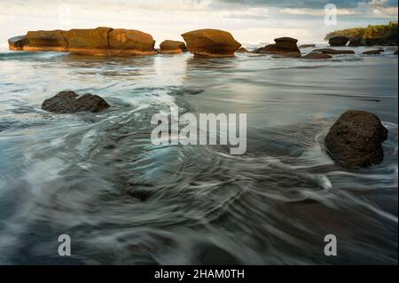 Bella gradazione di blu scuro ombra del mare su questa spiaggia di sabbia nera all'alba a Bali Foto Stock