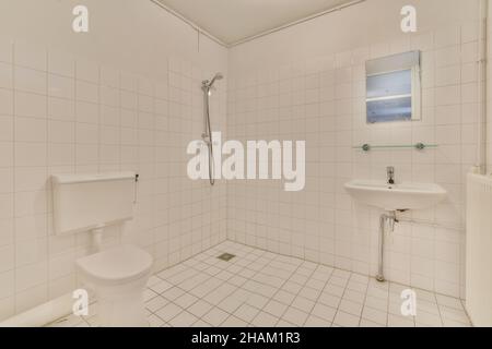 Bagno con pavimenti piastrellati di bianco e pareti bianche Foto Stock