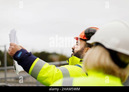 Ingegneri in abbigliamento riflettente discutere piani Foto Stock