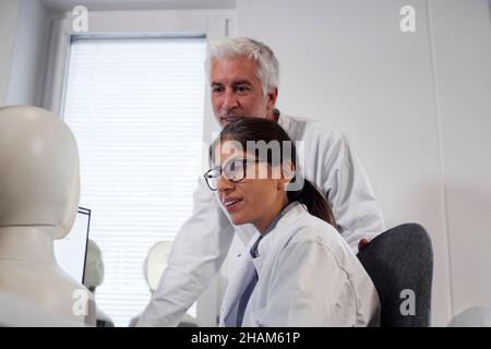 Studente e insegnante che lavora con il modello del volto illuminato Foto Stock