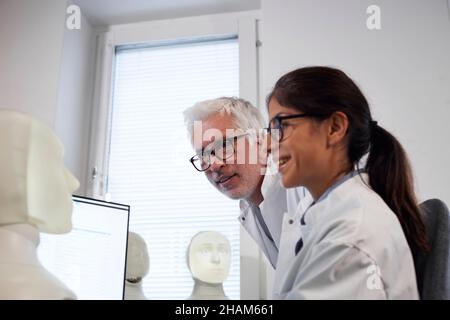 Studente e insegnante che lavora con il modello del volto illuminato Foto Stock