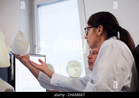 Studente e insegnante che lavora con il modello del volto illuminato Foto Stock