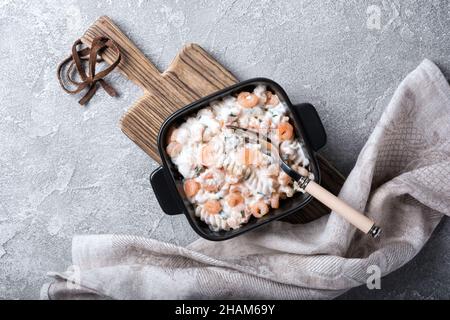 Vista dall'alto della pasta italiana rotini con gustosi gamberetti in salsa bianca cremosa su sfondo grigio di cemento Foto Stock