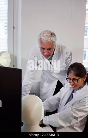 Studente e insegnante che lavora con il modello del volto illuminato Foto Stock