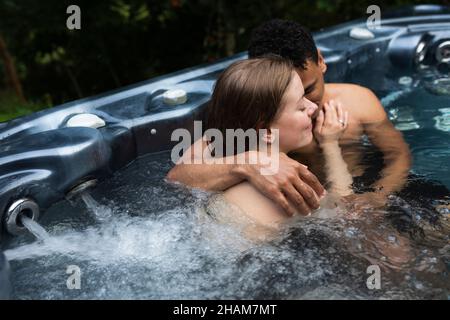 Una giovane coppia abbraccia la jacuzzi Foto Stock