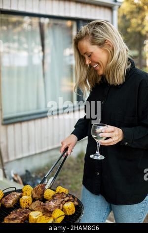 Donne che hanno barbecue sul patio Foto Stock