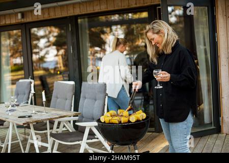 Donne che hanno barbecue sul patio Foto Stock