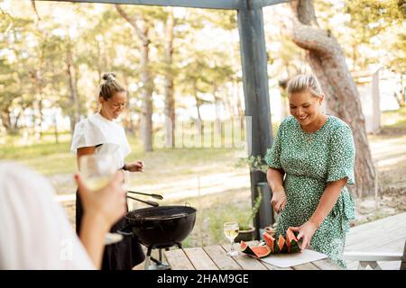 Donne che hanno barbecue sul patio Foto Stock