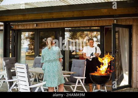 Donne che hanno barbecue sul patio Foto Stock