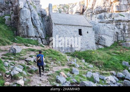 Piccola, antica, cappella, a,St Govans Chapel,Saint Govans,St Govans Head,Tiny,heremits,cell,next,to,Sea,water,Coast,Coast,Coastline,Pembrokeshire,West,Wales,Welsh,GB,Great Britain,British,St Govan's Chapel è una cappella situata a St. Govan's Head, Pembrokeshire nel Galles sud-occidentale. Costruito sul lato di una scogliera calcarea, l'edificio misura 20 x 12 piedi con pareti costruite in pietra calcarea, ed è composto da due camere, una nella parte anteriore e una nella parte posteriore. La maggior parte della cappella è stata costruita nel XIII secolo, anche se alcune parti di essa possono risalire al sesto secolo. Foto Stock