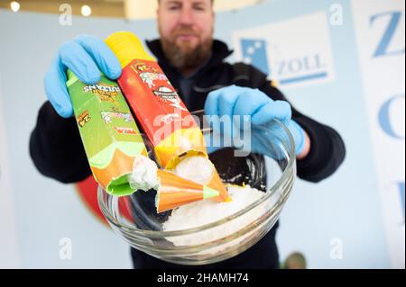 Colonia, Germania. 14th Dic 2021. Jens Ahland, portavoce doganale, tiene il met di cristallo sequestrato nella macchina fotografica, che sono stati nascosti nella parte superiore cava di un pacchetto di crayon . Le dogane hanno sequestrato circa 600 chilogrammi di droga solo nell'aeroporto di Colonia/Bonn nel novembre 2021. Credit: Federico Gambarini/dpa/Alamy Live News Foto Stock