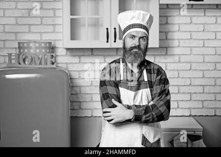 Un giovane uomo con il bearded, vestito con una camicia rossa e un grembiule bianco. Foto Stock