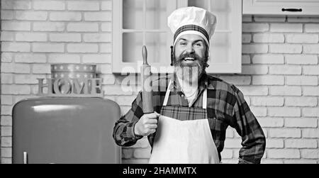 Lo chef cuoco con barba tiene una spilla su una cucina bianca. Foto Stock