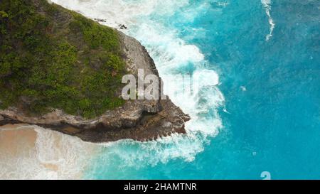 Le onde blu-bianche battono sulle rocce dell'isola di Nusa Penida vicino alla spiaggia di Kelingking. Foto Stock