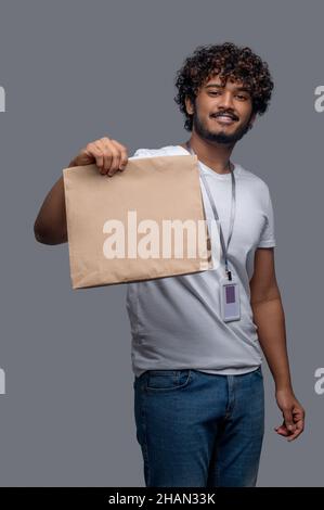 Ragazzo soddisfatto con il pacchetto in una mano guardando avanti Foto Stock