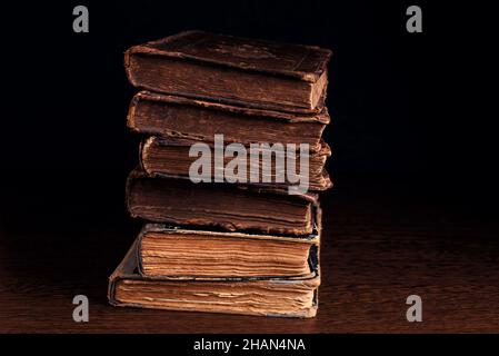 Primo piano di vecchi libri ebrei scaberati in pila nelle tenebre. Messa a fuoco selettiva Foto Stock