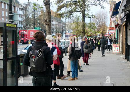 una lunga fila di persone si accaparrano per la vaccinazione di richiamo covid 19 su holloway road a nord di londra inghilterra regno unito dicembre 2021 Foto Stock