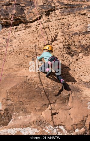 Una bambina di sette anni imparando a scalare la roccia nella zona di arrampicata di Wall Street vicino a Moab, Utah. Foto Stock