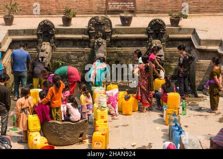 Gli uomini e le donne nepalesi ricevono acqua fresca dal Manga Hiti, una fontana d'acqua in Piazza Durbar, Patan, Nepal Foto Stock