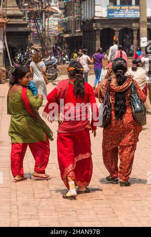 Tre donne nepalesi in abbigliamento tradizionale camminano attraverso la storica Durbar Square nella città medievale di Patan, Nepal. Foto Stock