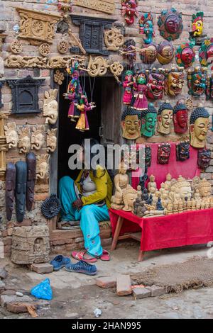 Una donna nepalese siede alla porta del suo negozio di souvenir nel villaggio medievale di Newari di Khokana, Nepal. Foto Stock