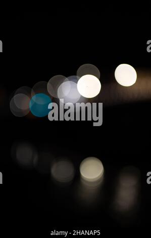 Luci colorate fuori fuoco sul ponte con riflessi nell'acqua Foto Stock