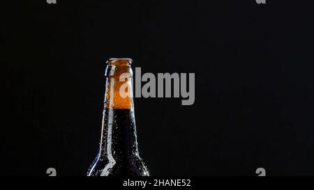 Primo piano di una mano che apre una bottiglia di vetro. Video. Bevanda alcolica isolato su sfondo nero, concetto di partito Foto Stock