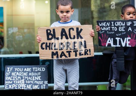 Due giovani manifestanti di BLM con bambini neri hanno la targa London 2020 Foto Stock