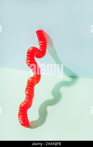 Il tubo pop curvo è appoggiato contro la parete. Vita morta moderna con giocattolo antistress. Foto Stock