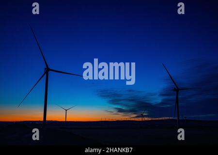 Sagome delle turbine eoliche sullo sfondo del tramonto. Foto Stock