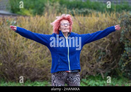 Anziana anziana donna nel suo 80s esercitandosi fuori facendo salti della stella in inverno. Vecchia signora mantenendo uno stile di vita sano e attivo. Foto Stock