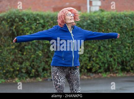 Anziana anziana donna nel suo 80s esercitandosi fuori facendo salti della stella in inverno. Vecchia signora mantenendo uno stile di vita sano attivo. Foto Stock