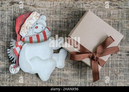 Regalo di Capodanno, sfondo Noel con ornamento a forma di orso e regalo su tavolo in legno con spazio copia. Natale o Noel saluto con scatola presente Foto Stock