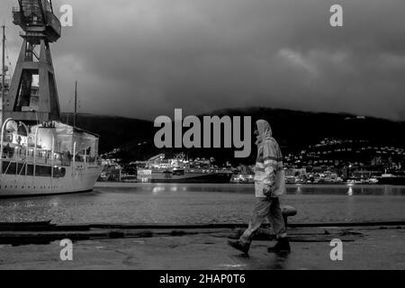 Lavoratore in un bacino di arenaria del vecchio cantiere BMV a Laksevaag, vicino al porto di Bergen, Norvegia. Il Royal Yacht in background, potenzialmente in attesa di entrare in Foto Stock