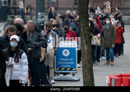 Manchester, Regno Unito, 14th dicembre 2021. I membri del thr pubblico fanno la fila ad un centro di vaccinazione nel centro di Manchester mentre i timori aumentano che la variante di Omicron costringerà il governo a chiudere le parti dell'economia. Credit: Jon Super/Alamy Live News. Foto Stock