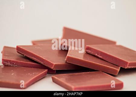 Il quarto tipo di cioccolato: Cioccolato al rubino affettato su una superficie bianca con spazio per la copia Foto Stock