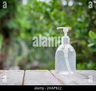 Sterilizzatore a mano bianco o flacone con gel di alcool su piano in legno con sfondo verde naturale Foto Stock
