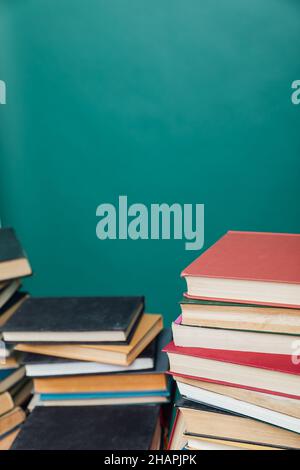 pile di libri per insegnare la conoscenza della biblioteca universitaria sfondo verde Foto Stock