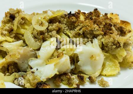 Merluzzo fatto in casa con pane di mais. Un piatto tipico portoghese con merluzzo grattugiato, patate fritte a fette, cipolle e pane croccante di mais. Foto Stock