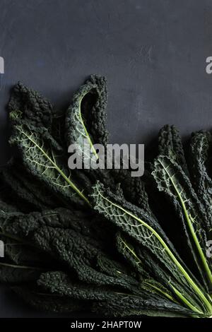 Foglie di cavolo fresco nero su sfondo grigio. Black Kale. Cucina italiana. Foto Stock