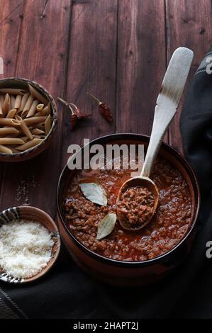 Bolognese fatto in casa o salsa di ragù servita in un recipiente rustico, su legno scuro. Direttamente sopra. Foto Stock