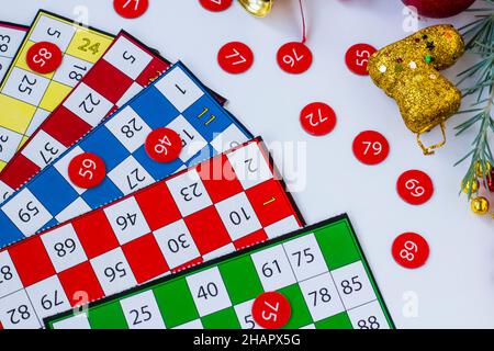 Carte colorate e numeri di gioco bingo su sfondo bianco con ornamenti di natale Foto Stock