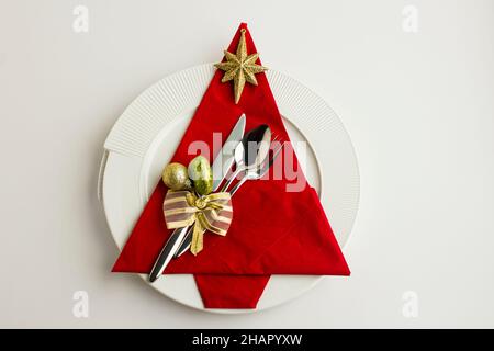 Fancy, tovagliolo di carta rosso piegato a forma di pino sul piatto con posate e ornamenti, vista dall'alto Foto Stock