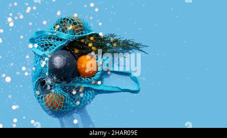 Composizione di Natale e Capodanno. Borsa blu con champagne, arance e ramo di abete. Borsa riutilizzabile. Sacchetti a rete ecologici. Foto Stock