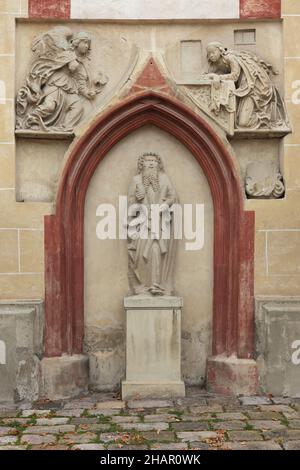 Statua gotica di Sant'Andrea Apostolo datata dal 1473 sulla facciata sud della Chiesa dell'Assunzione (Kostol Nanebovzatia Panny Márie) a Banská Bistrica, Slovacchia. L'Annunciazione è raffigurata sopra la Cappella di Sant'Andrea. Foto Stock